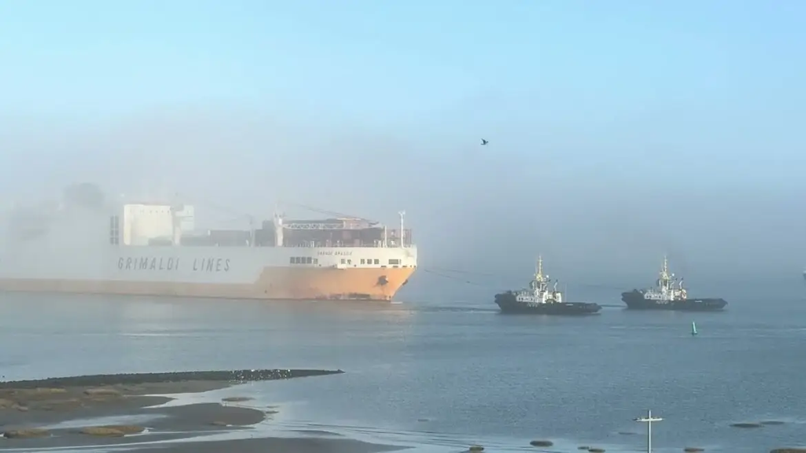 Rescue vessel tows burning cargo ship to safety.