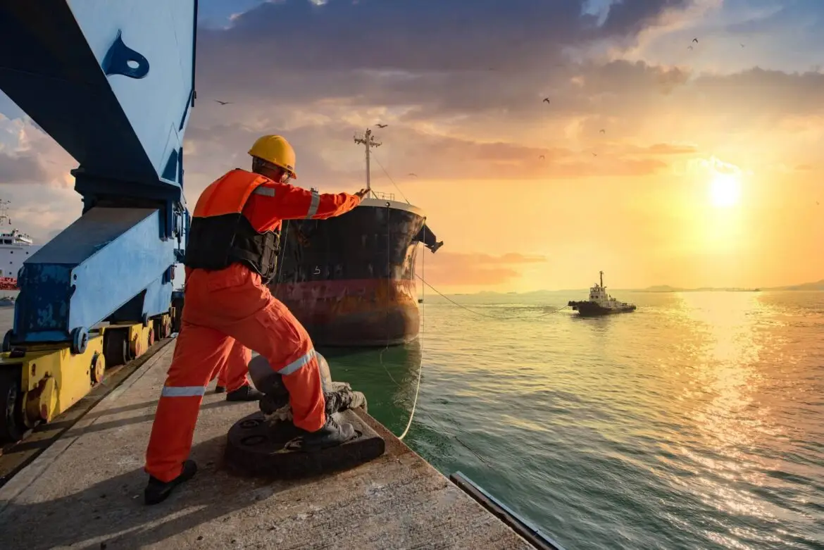 Diverse seafarers smiling on a ship's deck at sea.