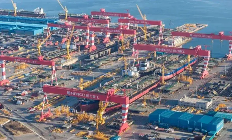 Aerial view of Hengli shipyard with multiple large red cranes and several VLCC and capesize vessels under construction.